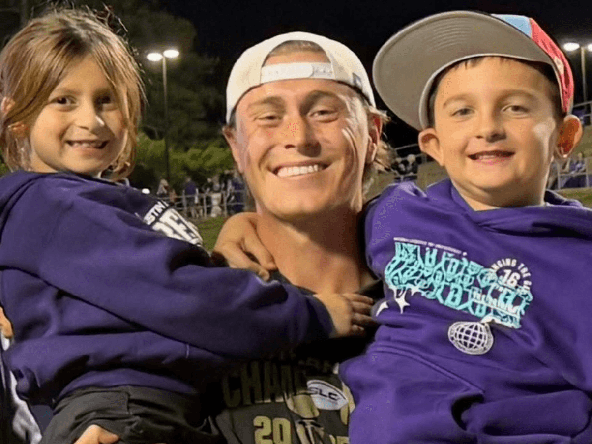 Tyler Henley smiling with two young fans.